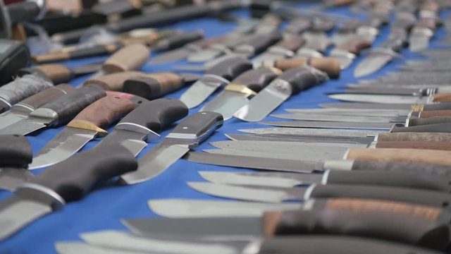 Knives on blue cloth. Cutting items are laid out. Handmade knives.