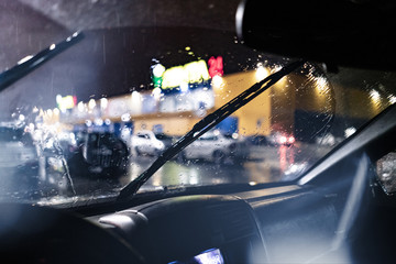 a view from inside the car of the windscreen wiper cleaning during night heavy rain - obrazy, fototapety, plakaty