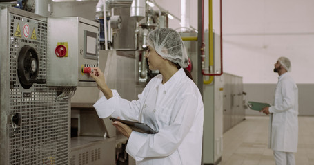 In the morning two beautiful engineers in manufacturing industry check the industrial machine and...