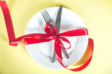 plate with spoon, knife and fork tied with red ribbon