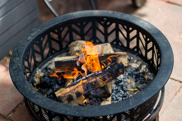 Fototapeta na wymiar Fire pit with burning logs on patio
