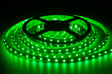 Green LED strip on reel with black background.