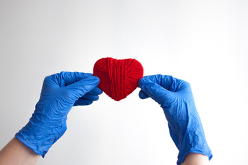 a hand in a blue glove holds a red heart. Medical concept. Copy space