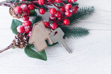 Flat layout on wooden background: figures, house, key and spruce branches / real estate 2020