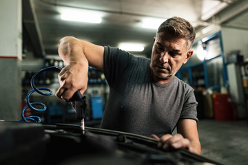 Fototapeta na wymiar Auto mechanic working on car engine in a repair shop.