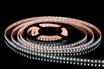 Cold white LED strip on reel with black background.