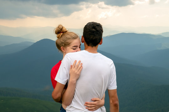Loving girl is sad while saying goodbye and hugs a young guy in the mountains.