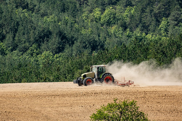 Obraz premium tractor plows a field near forest