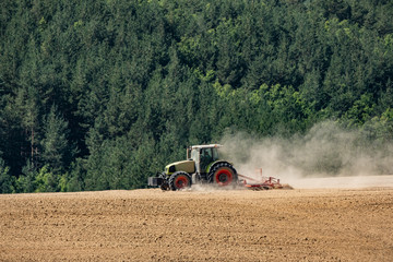  tractor plows a field near forest