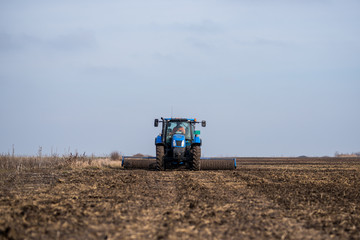 Fototapeta premium Tractor on the field cultivates the land.