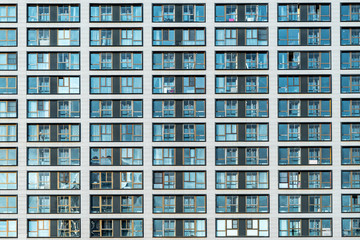 Fototapeta na wymiar White facade of a residential multi-storey building with large windows. Modern architecture. Real estate in a big city. Background from the wall of the house.