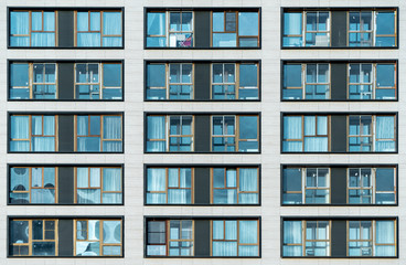 Fototapeta na wymiar White facade of a residential multi-storey building with large windows. Modern architecture. Real estate in a big city. Background from the wall of the house.