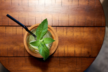 Glass of a Lemonade cocktail with ice cubes, tubule, lemon and mint. Top view