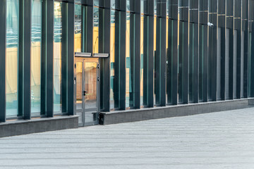 Spare entrance door to a glass office building. Hi-tech architecture. Modern urban public space.