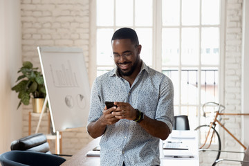 Happy mixed race young company worker texting message.