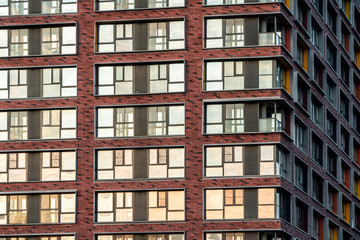 Brick facade of a residential multi-storey building with large windows. Modern architecture. Real estate in a big city. Background from the wall of the house.