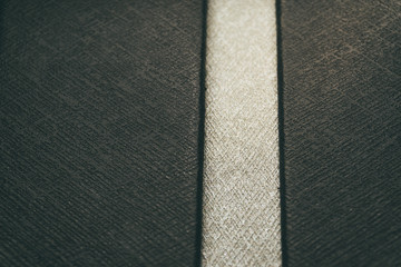 Close-up of customer grade realistic black plastic high detail textured leather imitation surface with white vertical line segment background