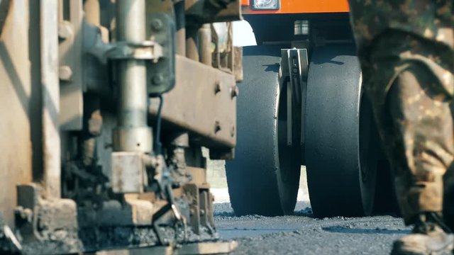 Wheels of an asphalt-placing vehicles in a front view. Road construction process.