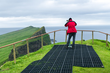 Foggy view of old lighthouse from viewpoint with tourist binoculars on the Mykines island, Faroe islands, Denmark. Landscape photography