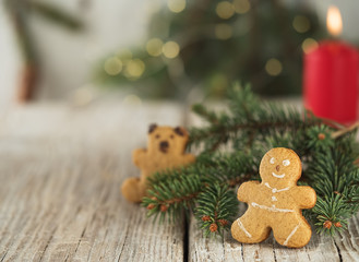 Christmas homemade gingerbread cookies, gingerbread man. On a wooden vintage background, near the branches of spruce and a burning candle. Close-up.