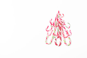 Christmas tree shape made of candy canes on white background. Top view