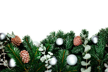 Green beautiful branches of pine tree with cones and Christmas silver balls on the white background. Place for the text.