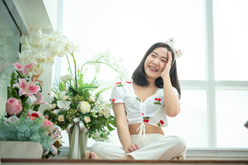 Fototapeta na wymiar A beautiful Asian woman is cute, bright and she is with beautiful flowers on the weekends.