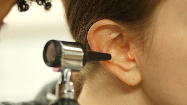 Doctor looking into a patient's ear with an 