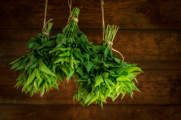 Nettle bunch on wooden background. Nettle harvest. Fresh herbs. Healthy diet.