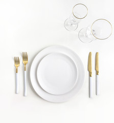 New luxury white ceramic plate, golden cutlery view from above on a isolated background. Top view..Knife and fork for a festive table for a wedding, birthday or party.