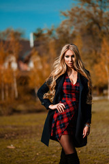 Sexy long-haired blonde in a checkered dress walks in the autumn square. Photoshoot in the autumn...
