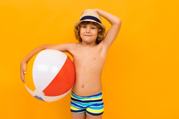 Red-haired boy with a summer hat and a swimming circle on a yellow background