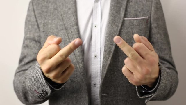 caucasian solid man in gray jacket and speckled shirt on white background showing his middle fingers on both hands and shake it. disrespectful flip off finger sign, gesture to ill-wishers and envious