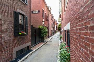 Fototapeta na wymiar Narrow alley lined with traditional American red brick houses and gas lit lamp posts. Beacon Hill, Boston, MA, USA.