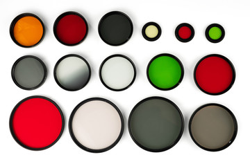 Glass round filters of different colors and sizes are isolated on a white background.
