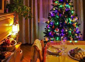 Christmas tree at home by the window. Christmas toys decorations. Decorative lamp by the window. Christmas New Year. The lights in the window. Glass colored balls ceramic figures on the Christmas tree