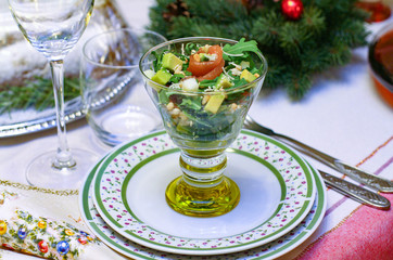 Salmon salad in a glass bowl. Plates and glasses on the festive table. Fresh tasty salad with fish for the holiday. Christmas table. Gala dinner at home. Tasty appetizer. Christmas and New Year.