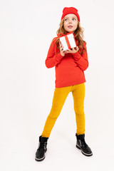 girl in a red hat holds a gift over white studio background
