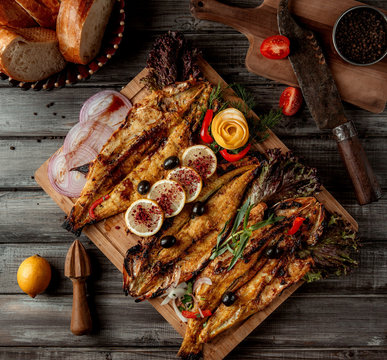 fried fish with sumakh and onion on wooden board