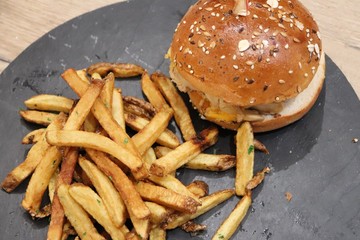 Hamburger accompagné de frites sur une planche en ardoise