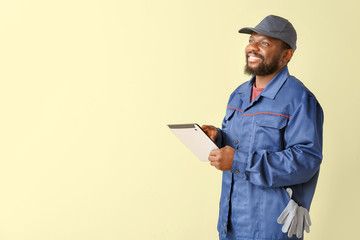 African-American car mechanic with tablet computer on color background