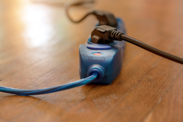  blue extended socket with many adapters and black cables on wooden floor