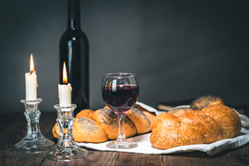 Shabbat Shalom. Challah bread, shabbat wine and candles on wooden table.