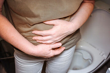 Caucasian woman is sitting on the toilet. Concept of the problem with digestion.
