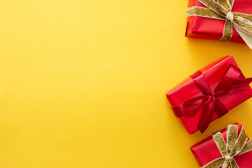 Top view of red gift boxes with ribbon over colorful yellow background. Valentine's day, Christmas or birthday concept.