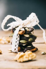 Close up of a pack of healthy snacks made from almonds, walnuts, hazelnuts and pumpkin seeds tied up with white lace on a wooden base