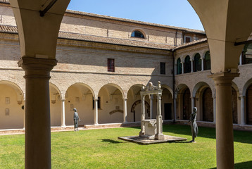 Courtyard with decorated columns, arches and green lawn of old Franciscan friars cloister near the Dante's Tomb and Basilica of San Francisco in Ravenna, Italy