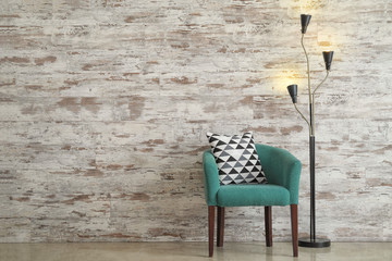 Fototapeta na wymiar Cozy armchair with lamp near wooden wall in room
