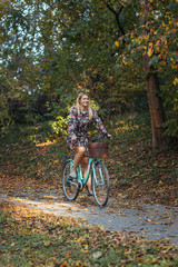 Naklejka premium Young woman riding a bicycle in the park in autumn