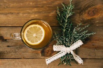 Crystal mug filled with green tea with a slice of lemon inside of the beverage next to aromatic...